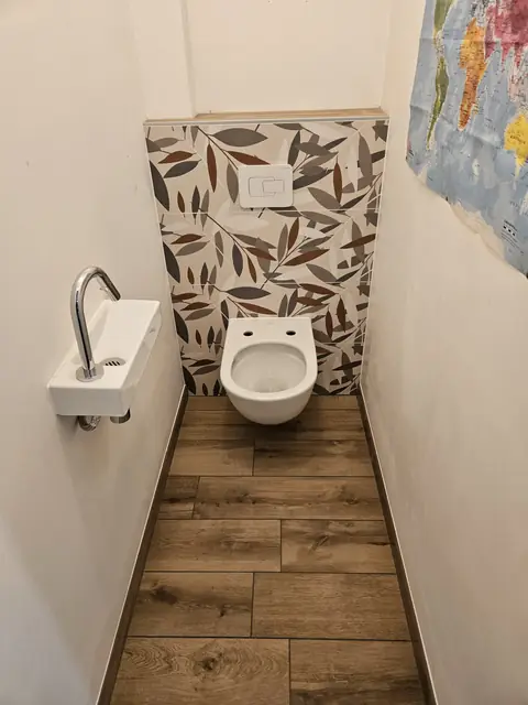 WC suspendu avec mur à motifs feuillage et sol imitation bois